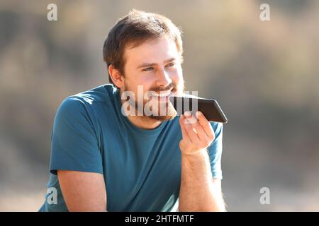 Happy man using voice recognition on cellphone contemplating outdoors Stock Photo