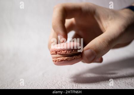 caucasian hand of boy holding pink macaroon with copy space Stock Photo
