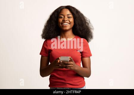 Cool App. Portrait Of Positive African American Woman With Smartphone In Hands Stock Photo