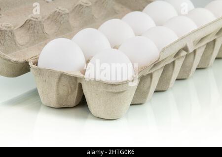 Eggs carton on reflective white background. Stock Photo