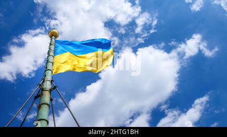 Ukrainian flag fluttering on the wind on the old flagpole against blue dramatic sky Stock Photo