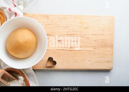 Baking ingredients and kitchen utensils on a white background top view. Preparing heart sugar cookies. Baking background. Flour, eggs, sugar, spices, Stock Photo