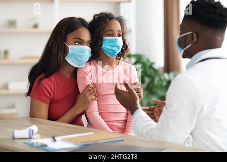 Sick daughter and mother in face masks visiting pediatrician Stock Photo
