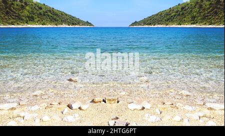 Abstract view of pebble beach in silver reflection in a beautiful blue sea lagoon and untouched and unpolluted nature Stock Photo