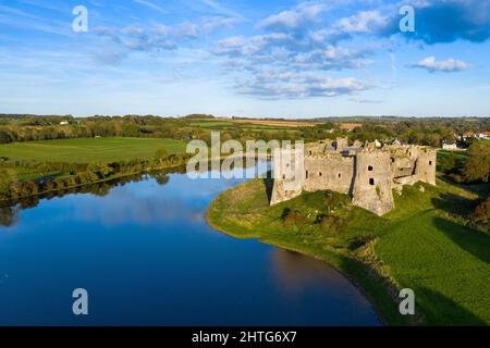 Aerial shot of Carew Castle with a reflection on a river and a green valley under a cloudy blue sky Stock Photo