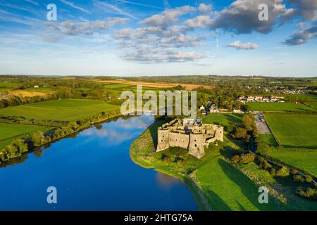 Aerial shot of Carew Castle with a reflection on a river and a green valley under a cloudy blue sky Stock Photo