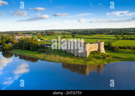 Aerial shot of Carew Castle with a reflection on a river and a green valley under a cloudy blue sky Stock Photo