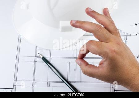 Man like the project or architectural plan or business with showing italian like gesture. Blueprint with pencil and helmet on the background. Stock Photo