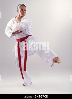 Shes got a solid kick. Shot of a young woman doing karate. Stock Photo