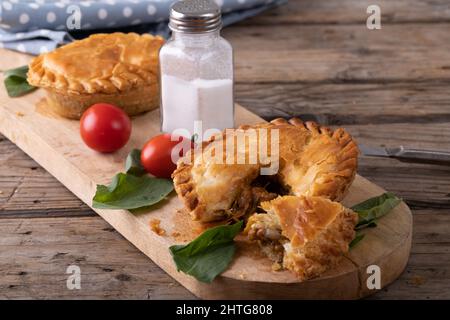 High angle view of stuffed pies with tomatoes, herbs and salt shaker on ...