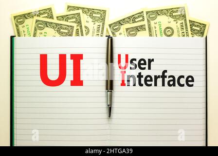 UI user interface symbol. Concept words UI user interface on white note. Metallic pen. Dollar bills. Beautiful white background. Copy space. Business Stock Photo