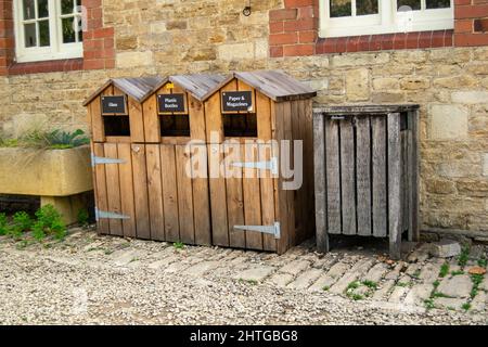 Three wooden recycling bins with non recycling waste bin next to them. Paper, magazines, glass and plastic bottles recycle units standing by the Stock Photo