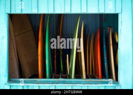 Set of colorful surfboards for rent or sell. Surf boards displayed next to a beach Stock Photo