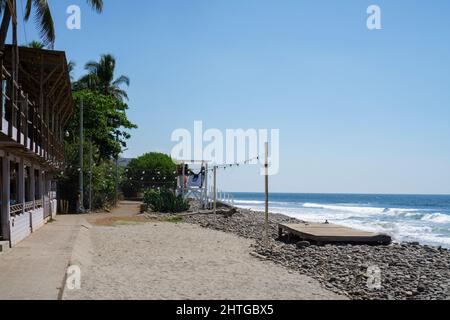 El Tunco, El Salvador - January 29, 2022: Rocky beach with buildings on a summer day. Lifeguards standing on the chair Stock Photo