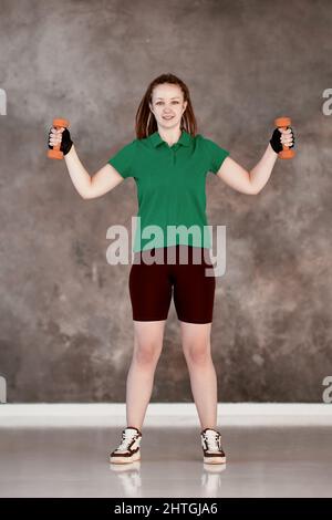 Aerobic exercise by woman who holds dumbbells during fitness in gym. Stock Photo