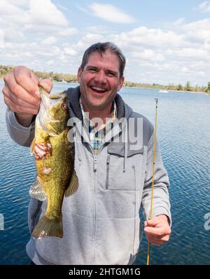 Happy fisherman holding his giant Rock Bass fish close to the