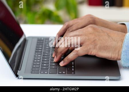 Closeup shot of an unrecognizable man working on a laptop at home Stock Photo