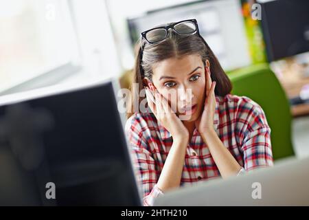 This cant be right. Shot of a young woman looking surprisingly at her computer screen. Stock Photo