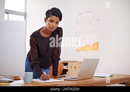 A productive day. A beautiful young woman making notes in her office. Stock Photo