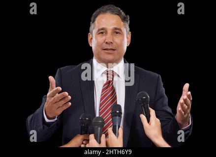 Pandering to the press. Portrait of a mature man giving a press conference on a black background. Stock Photo