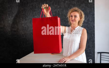 shopping in a clothing store, a woman seller giving a shopping package, selling and buying clothes. Shopping concept for women Stock Photo