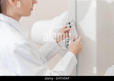 Hospital Radiology Room. Xray fluorography device remote control. Doctor radiologist in gown adjusting the X-ray machine for radiography. Medical Stock Photo