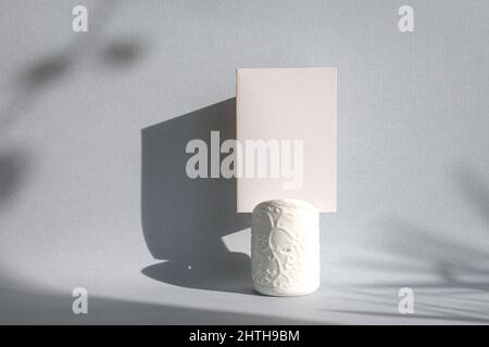 Blank white card on top of a white holder with shadow on wall. Mock-up template as greeting or invitation for event. Stock Photo