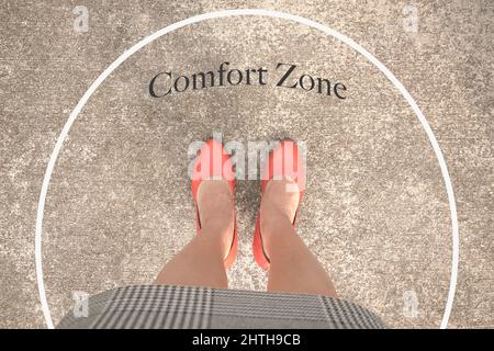 Woman with orange heels standing inside a white circle with the word, Comfort zone. Top view. Stock Photo