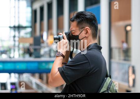 Portrait of an Asian male photographer wearing face mask at work. Stock Photo