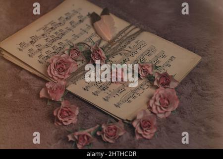 Closeup shot of music notes, heart-shaped flowers, and feathers - concept of romance Stock Photo
