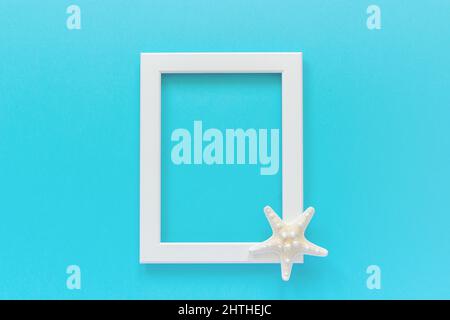 White frame with starfish on blue background. Creative Flat lay Top view Template for postcard, design Copy space for text. Stock Photo
