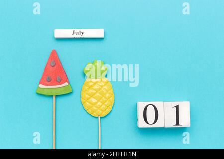 Wooden cubes calendar July 1. Summer fruits pineapple, watermelon on blue background. Concept hello July Copy space Creative Top view Flat lay. Stock Photo