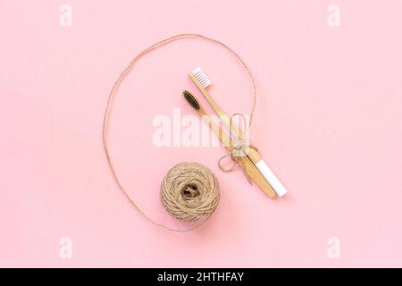 Two natural eco-friendly bamboo brushes with white and black bristles, tied with twine on pink background. Copy space for text or your design. Top vie Stock Photo