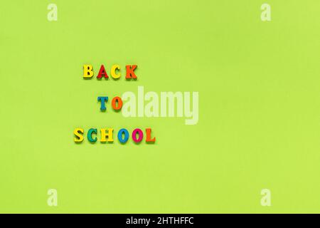 Text Back to school from multi colored letters on green paper background Concept Education Top view Copy space Template for your design. Stock Photo