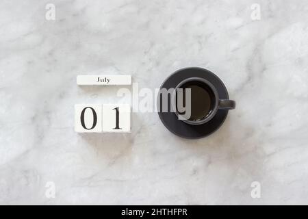 Office or home table desk. Wooden cubes calendar July 1st and cup of coffee on marble background Concept stylish workplace Flat lay Top view Minimal s Stock Photo