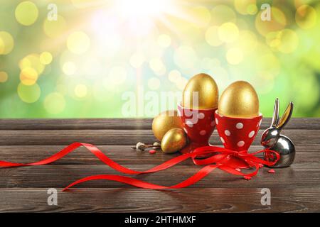 Painted Easter eggs and figurine of bunny on table against blurred background Stock Photo