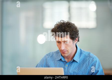 Doing some research online. Cropped shot of a handsome businessman working in the office. Stock Photo