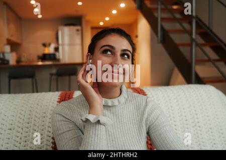 Caucasian female student relaxing on sofa listening to music with earphones Stock Photo