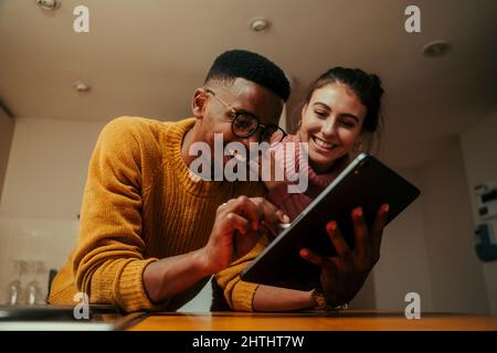 biracial couple working from home typing on digital tablet Stock Photo