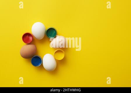 Chicken eggs and paints on a yellow background for colorful easter Stock Photo