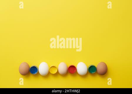 Chicken eggs and paints on a yellow background for easter Stock Photo