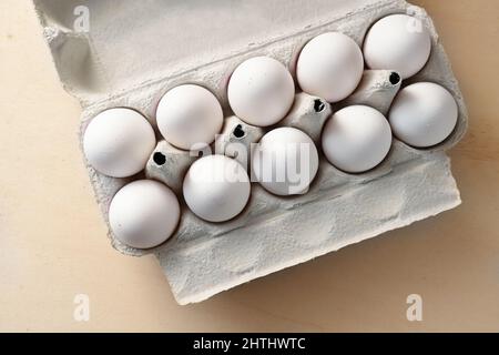 Organic white eggs in a cardboard container on a wooden table, high angle view from above, selected focus Stock Photo