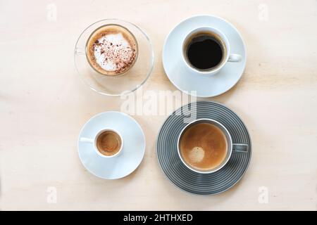 https://l450v.alamy.com/450v/2hthxed/group-of-cups-with-various-coffee-espresso-cappuccino-lungo-black-and-with-crema-on-a-light-wooden-table-copy-space-high-angle-view-from-above-s-2hthxed.jpg