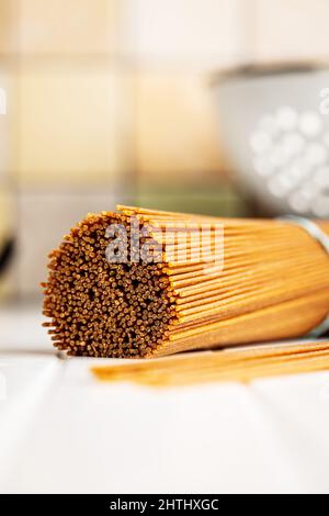 Uncooked whole grain spaghetti. Raw pasta on a white table. Stock Photo