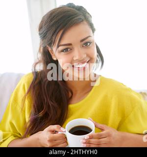 Easing into the day with a nice cup of coffee. Portrait of a young woman having a cup of coffee at home. Stock Photo