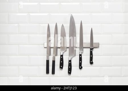 Six Japanese knifes hanging on white wall tile Stock Photo