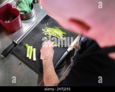 Cook cutting a celery using a sharp knife in a restaurant Stock Photo