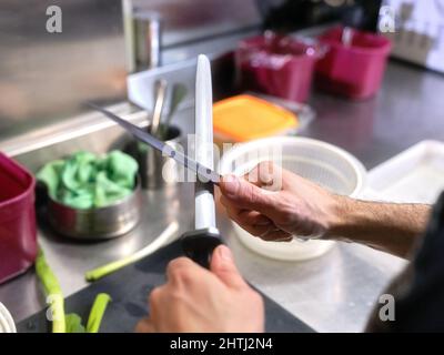 Cook sharpening kitchen knives in a restaurant Stock Photo