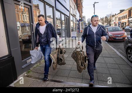 Picture shows Ukrainian men walking along the high street carrying flak-jackets after buying army surplus at G4 Echelon Military Supplies ahead of lea Stock Photo