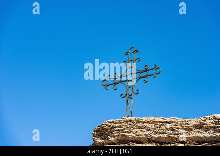 Wrought iron religious cross above a rock karst formation. Lessinia Plateau Regional Natural Park, Erbezzo, Verona Province, Veneto, Italy, Europe Stock Photo